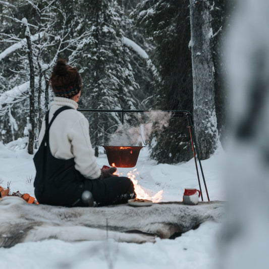 Person sitting by a campfire in a snowy forest
