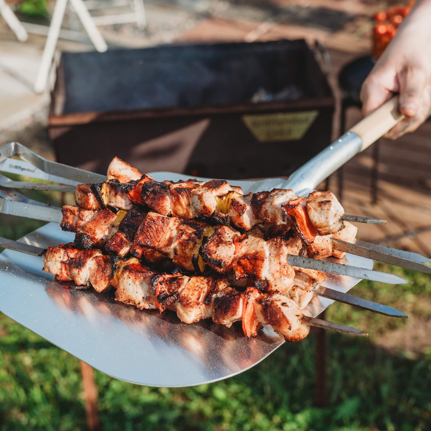 GrillSymbol Naked Chef XS charcoal grill in outdoor setting, showcasing compact design and grilling surface.