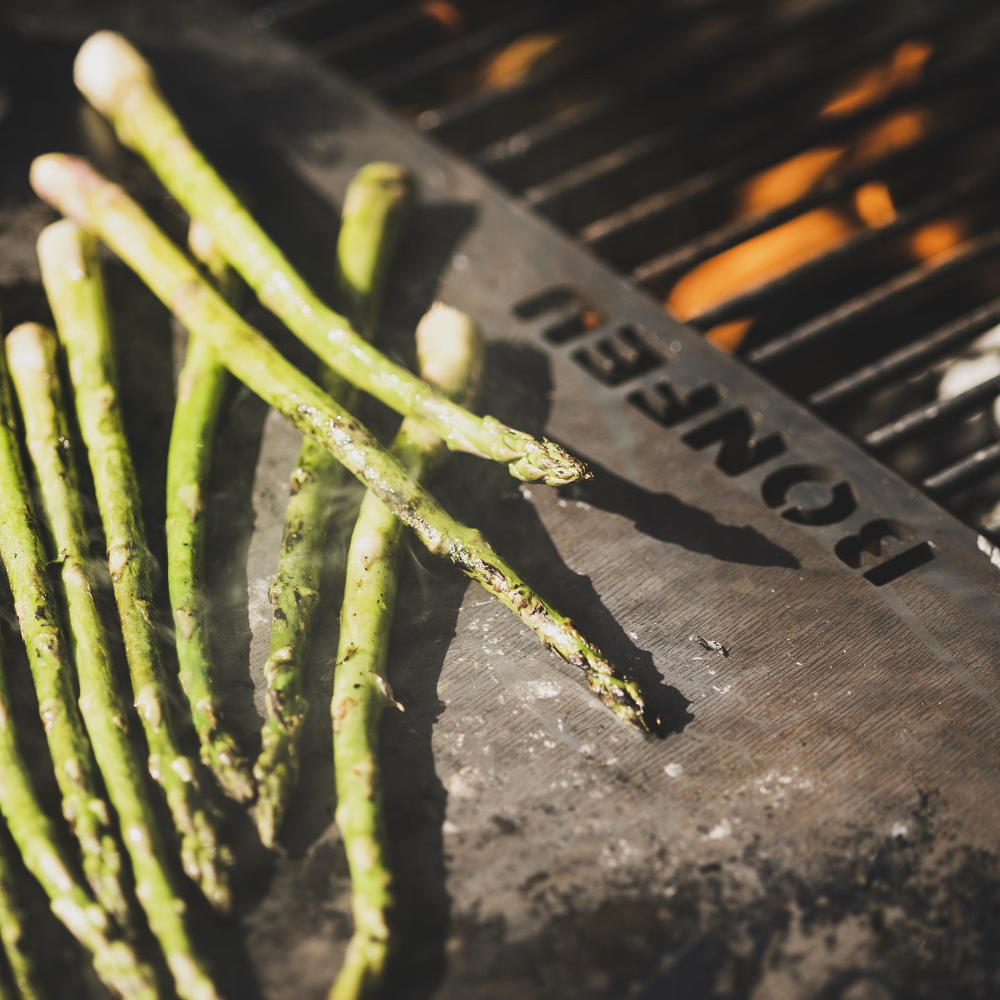 Grilled asparagus on a barbecue with 'BonFeu' branding.