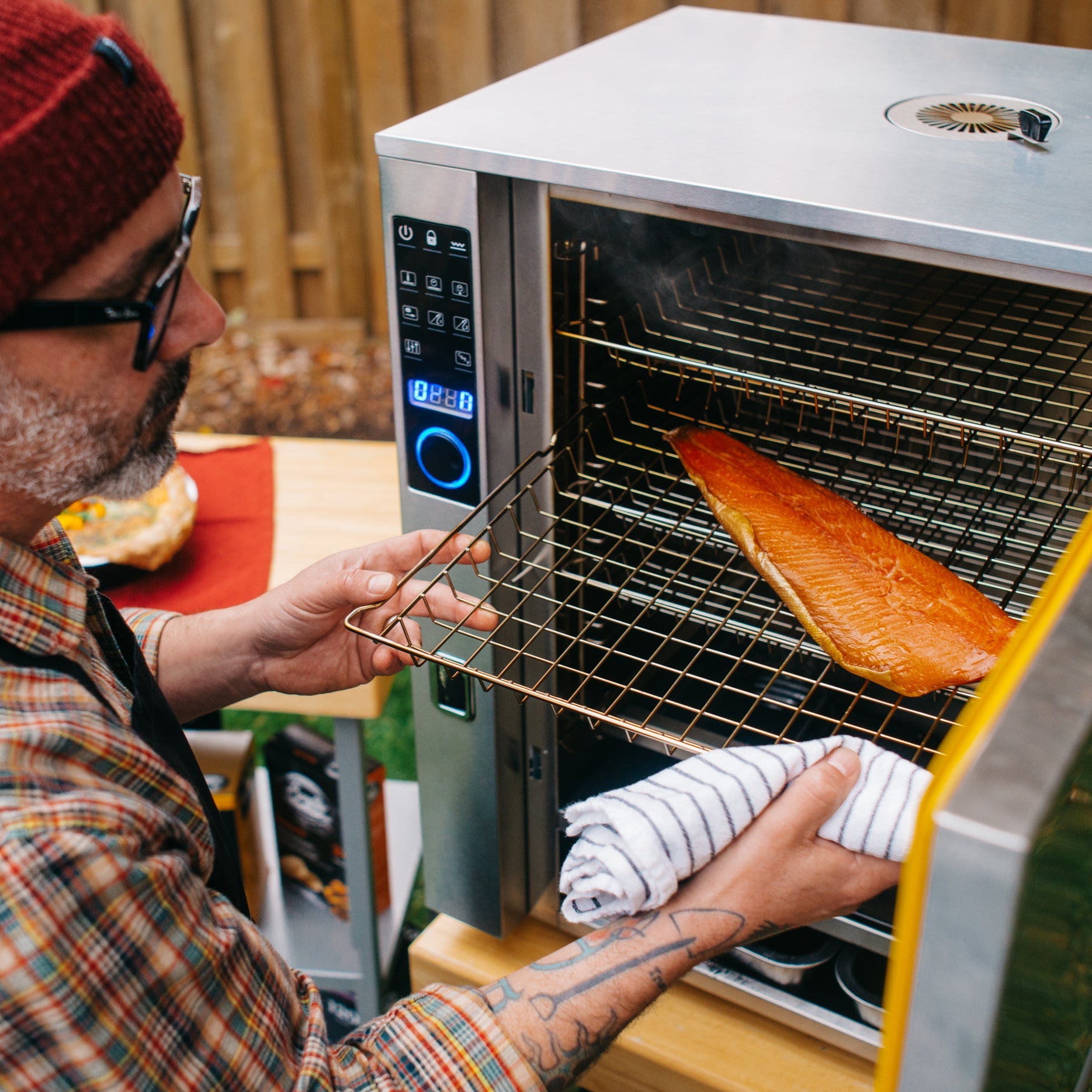 Person cooking salmon in a portable oven outdoors