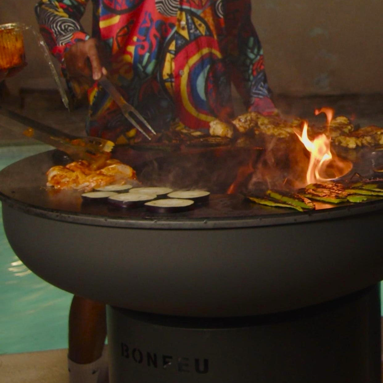 Man grilling food on a barbecue by a poolside