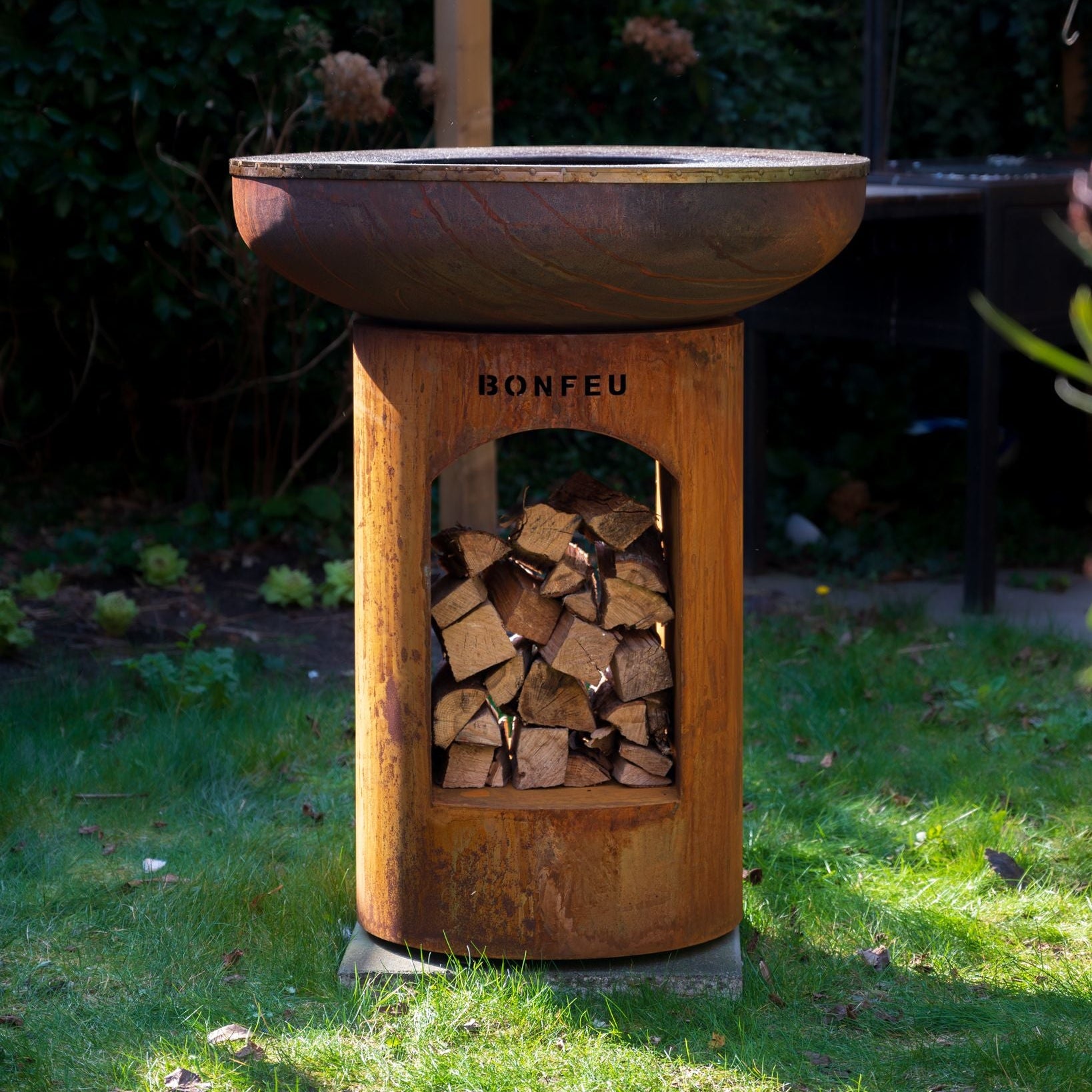 Wooden fire pit with firewood storage on a grassy area