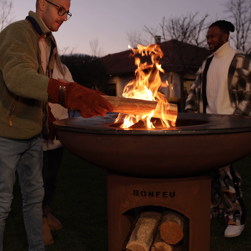 Two people around a fire pit with 'Bonfeu' branding at dusk.
