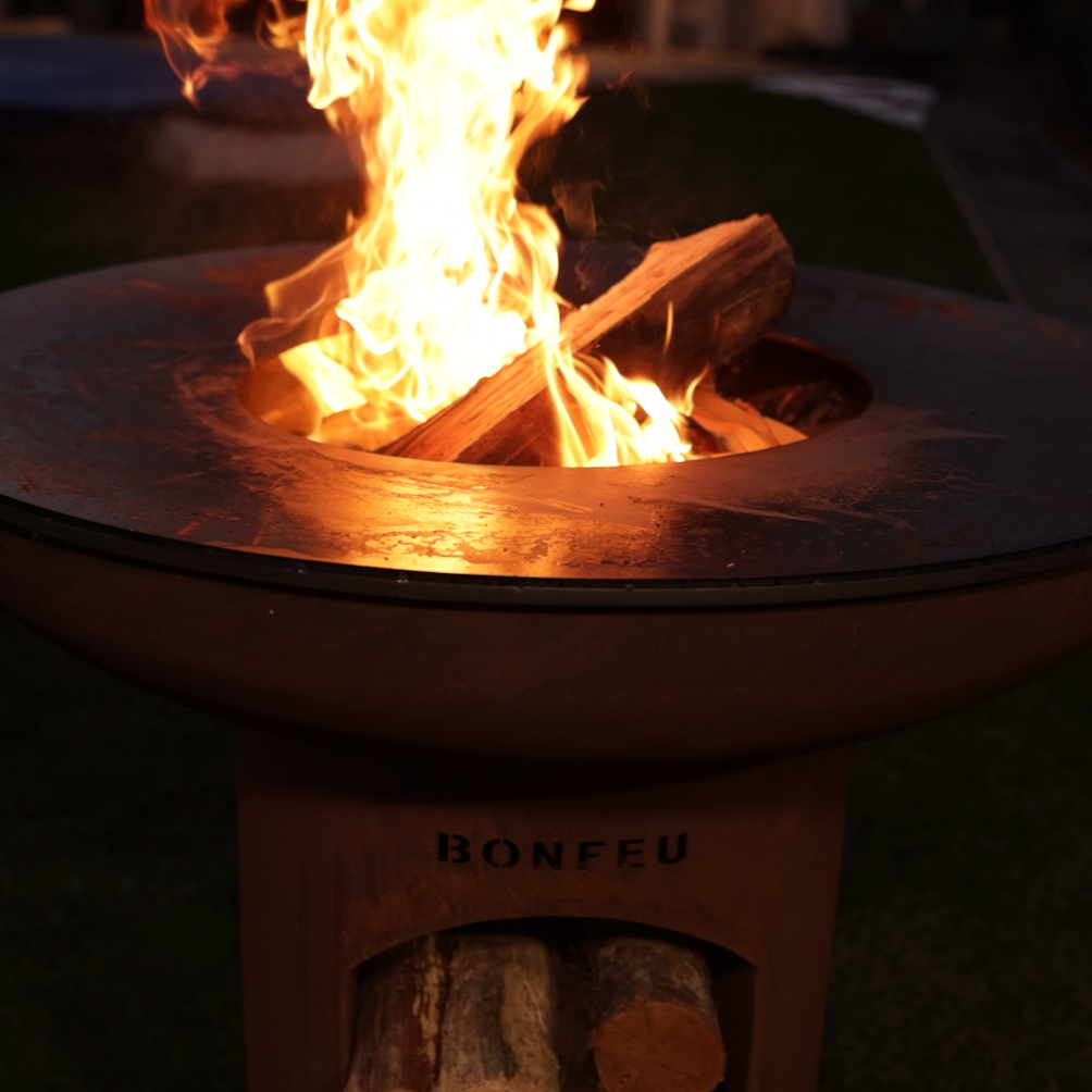 Fire pit with flames glowing in the dark, featuring the brand BonFeu