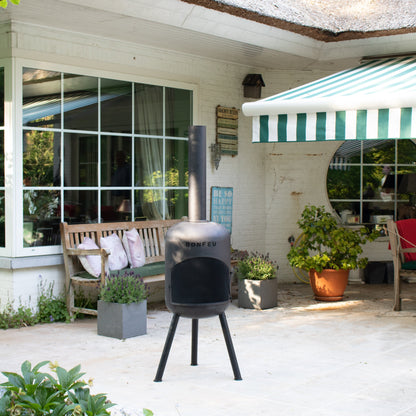 Outdoor patio area with a barbecue grill, bench, and plants in front of a house.