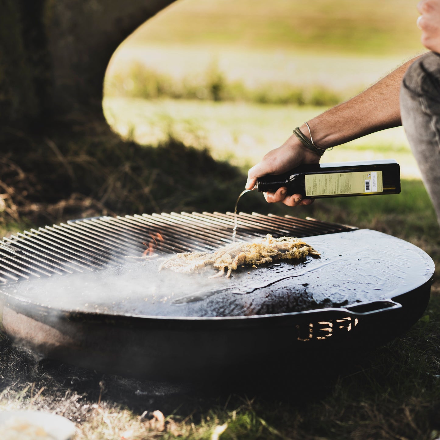Person grilling outdoors with a scenic background