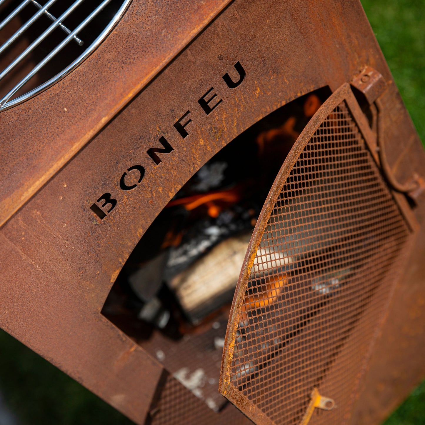 Rust-colored fire pit with 'BONFEU' branding on a grassy background