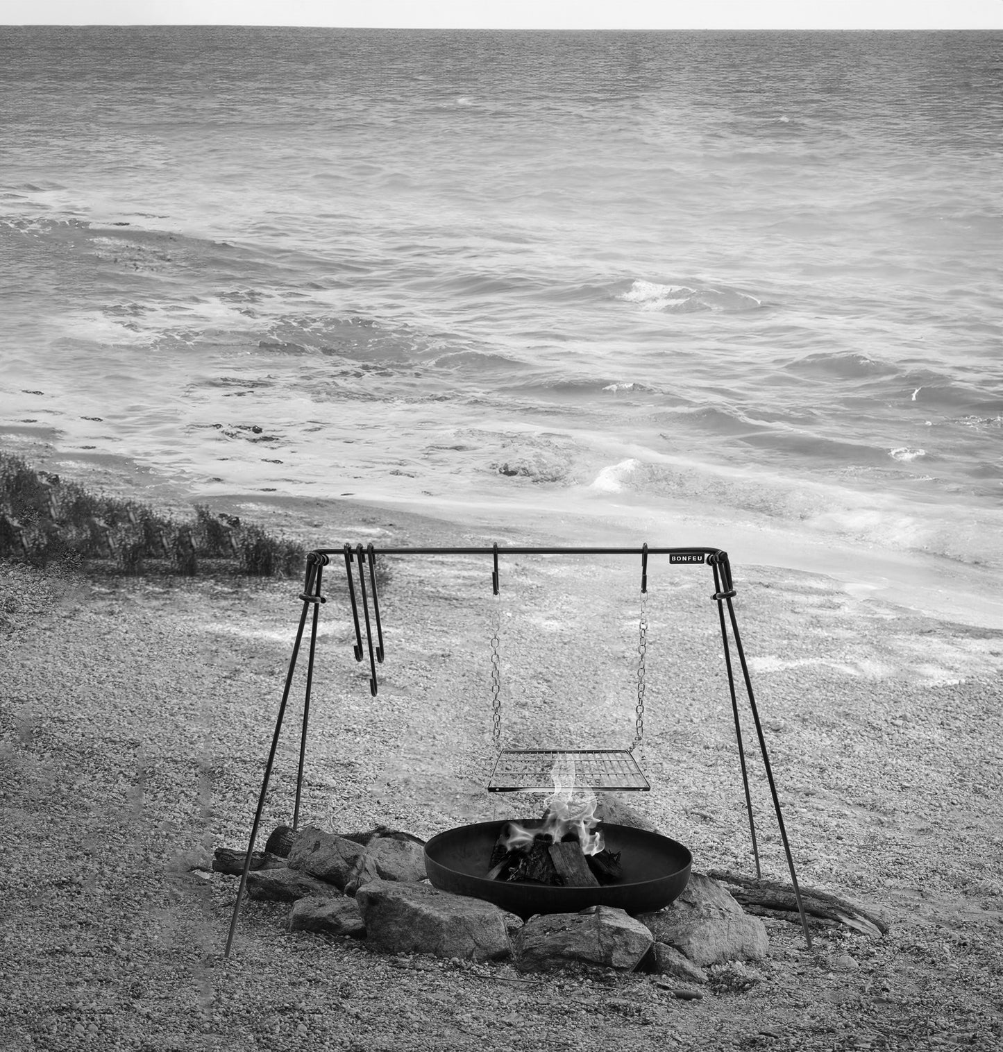 Fire pit with swing set on a grassy area near water