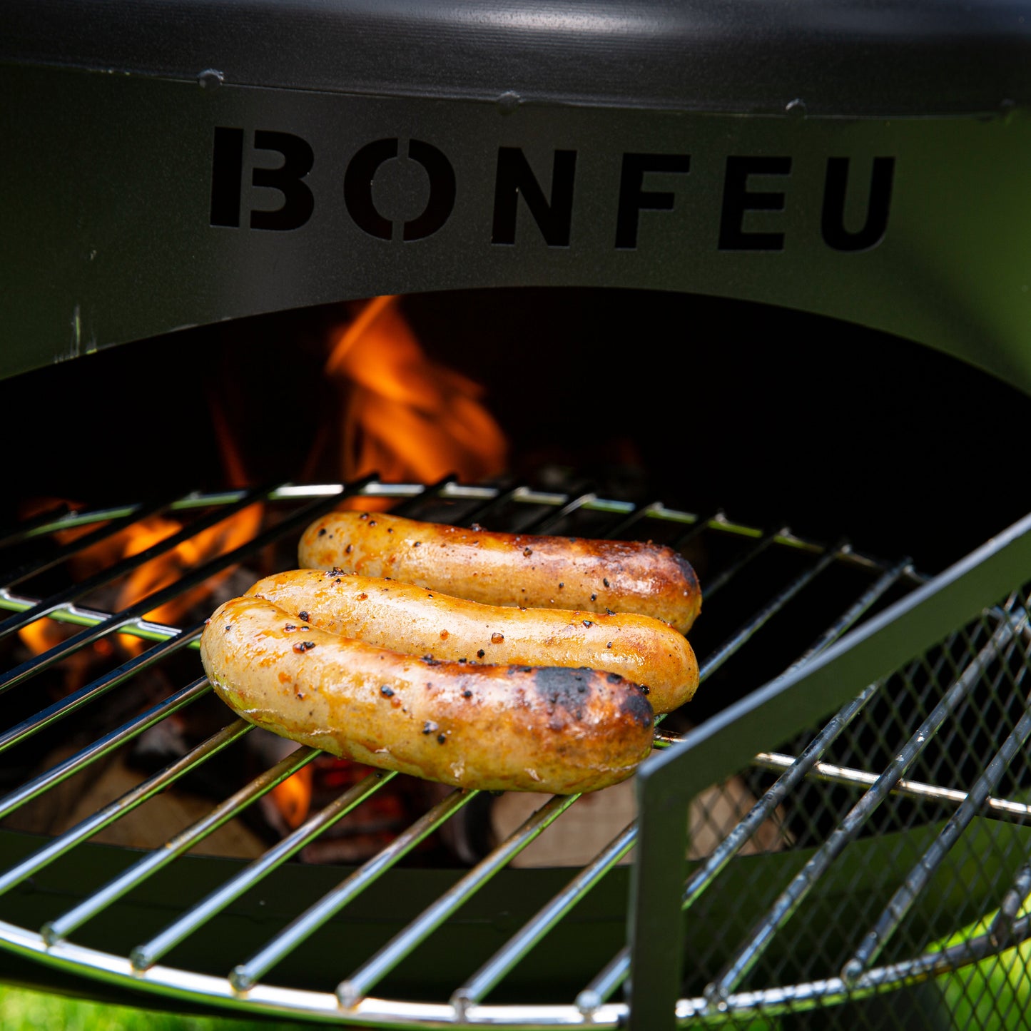 Bonfeu grill with sausages cooking on a grassy background
