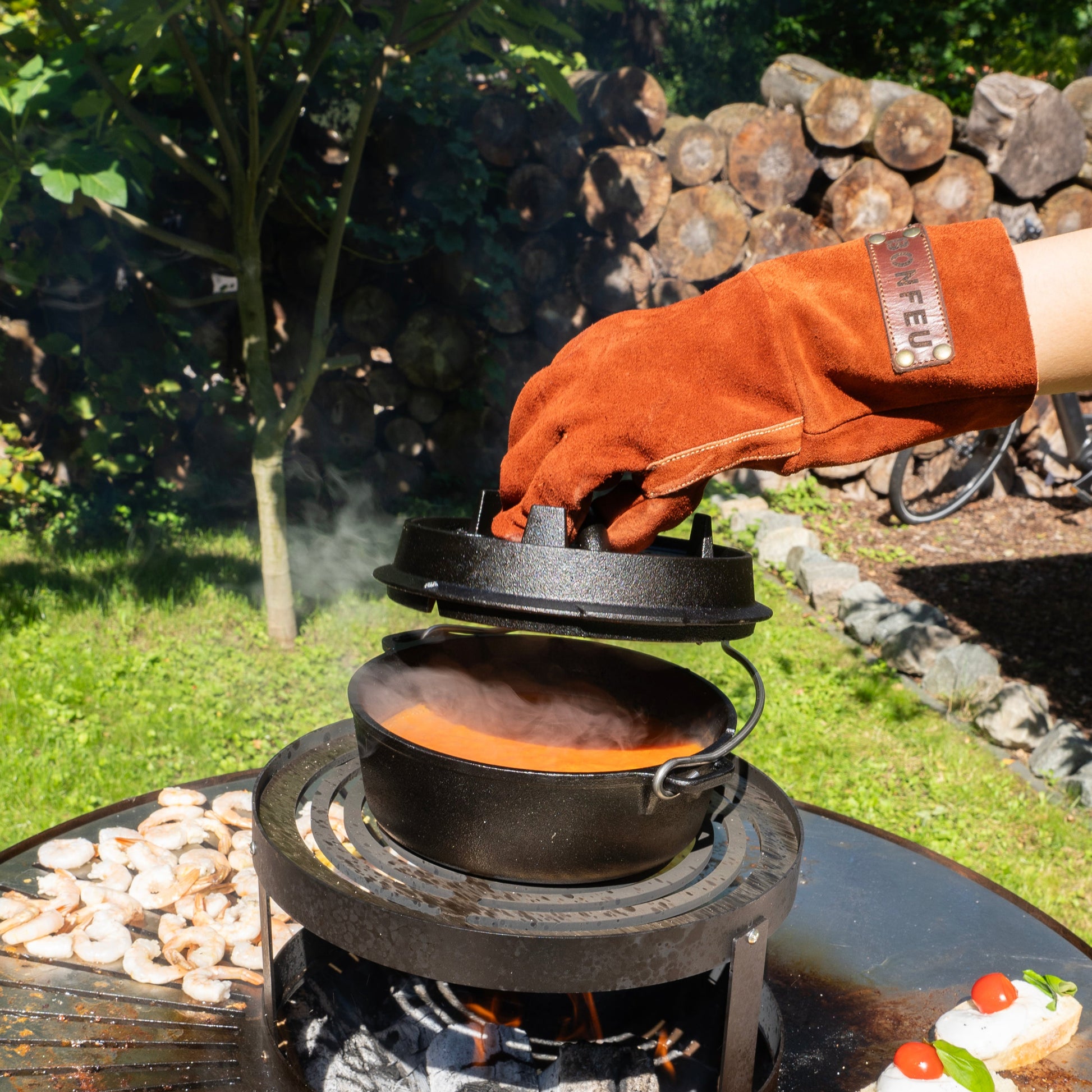 Person using a portable stove with a Dutch oven outdoors, surrounded by nature.