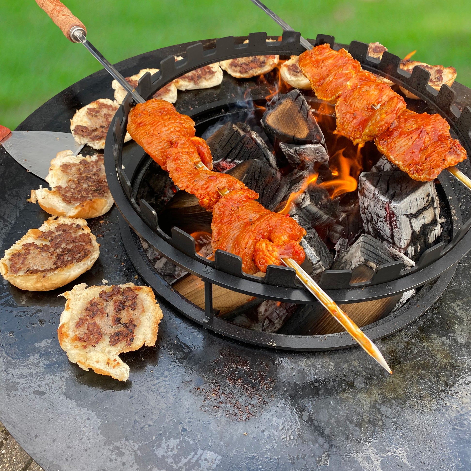 Skewers with food over a fire pit on a patio