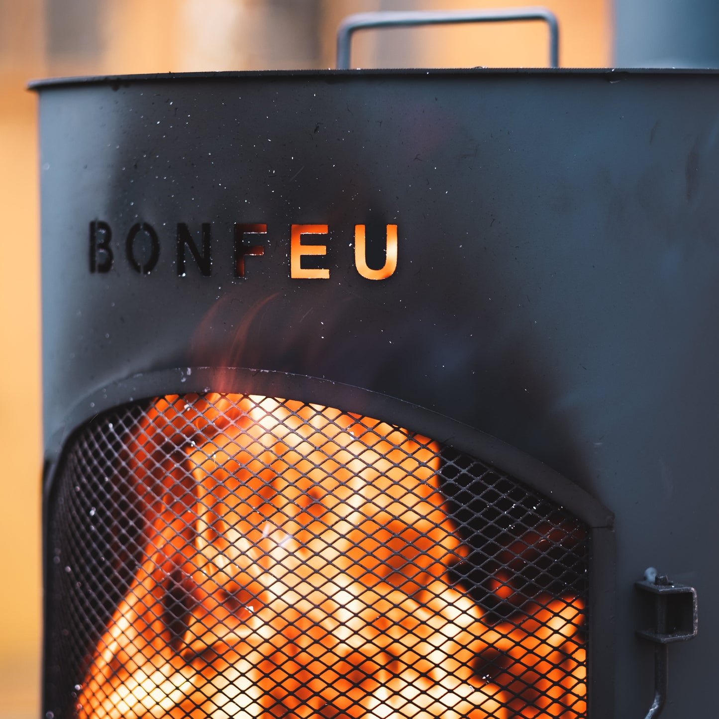 Black fire pit with 'BONFEU' branding and flames inside, blurred background