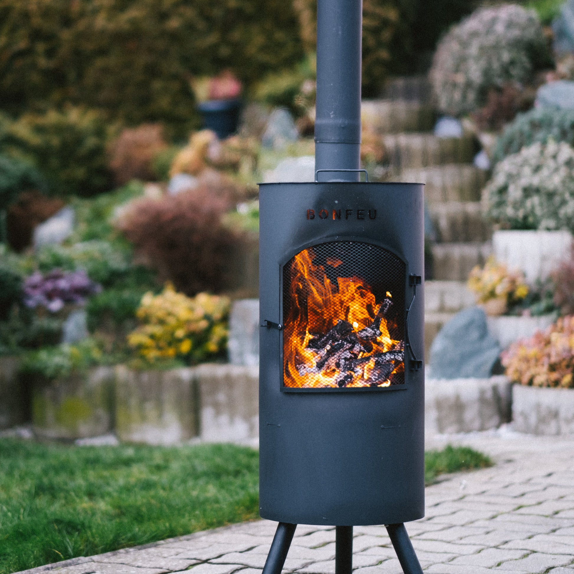 Outdoor fireplace with flames burning in a garden setting