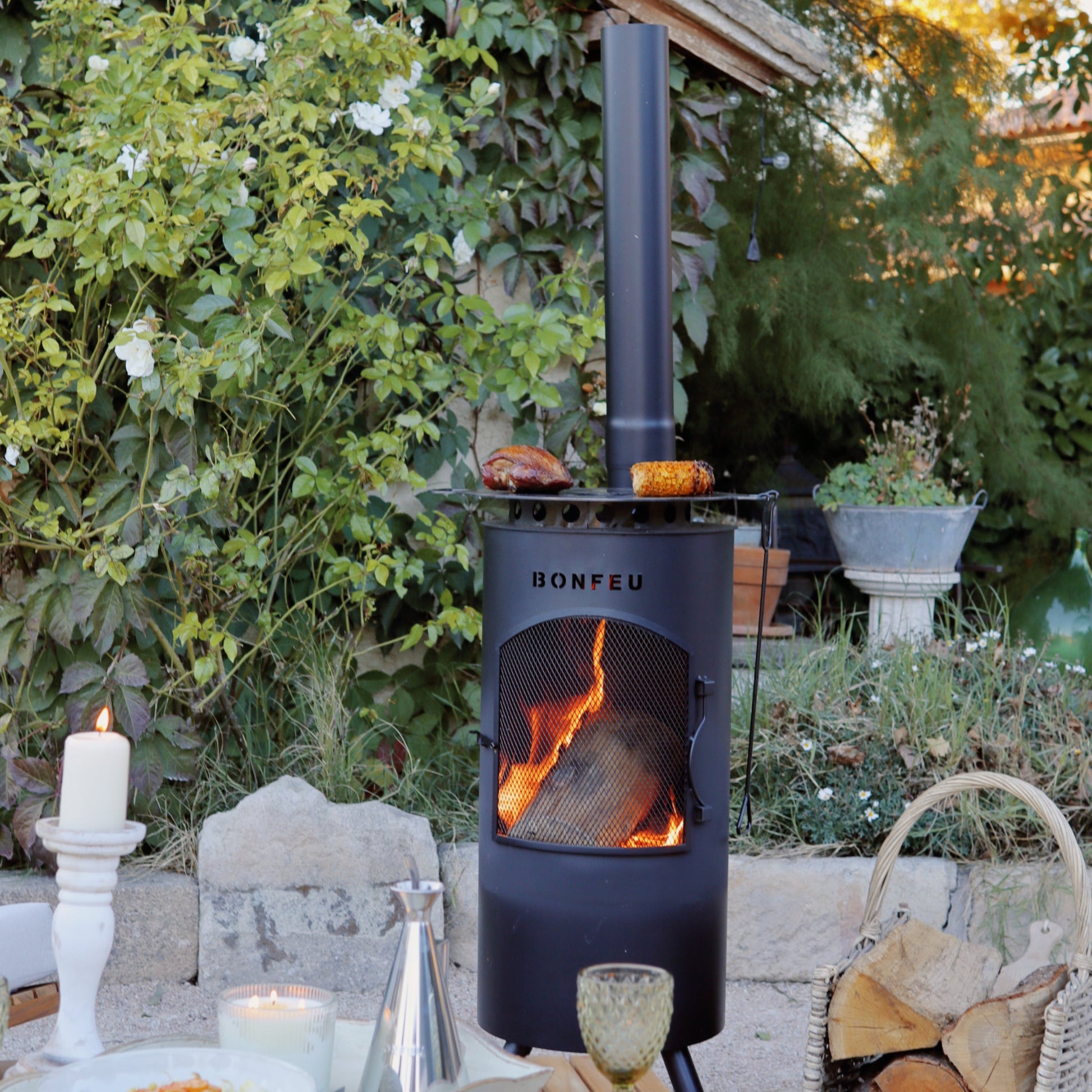 Outdoor setting with a wood stove, table, and garden decorations.