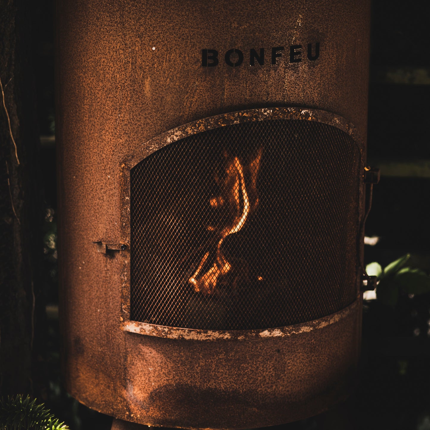 Rust-colored 'Bonfeu' outdoor heater with glowing interior in a dark setting