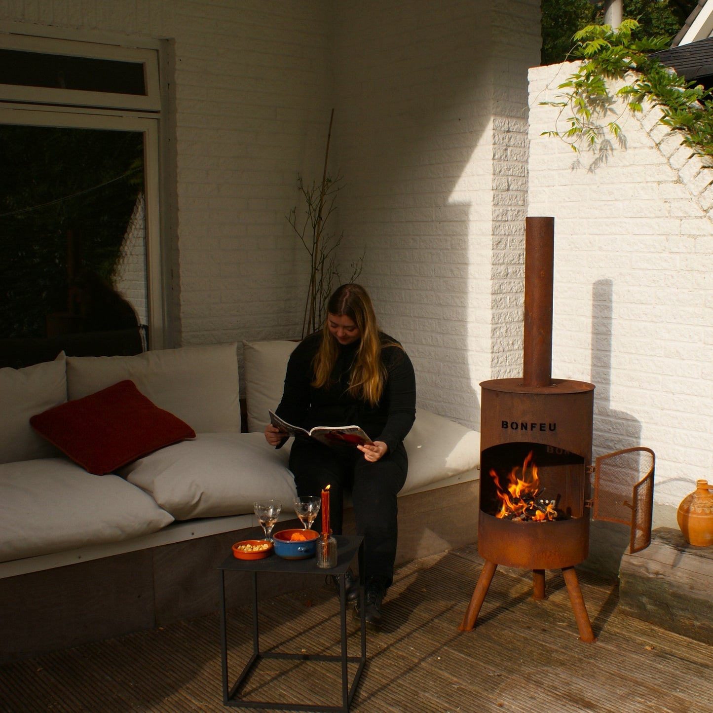 Woman sitting on a patio with a fire pit and outdoor furniture
