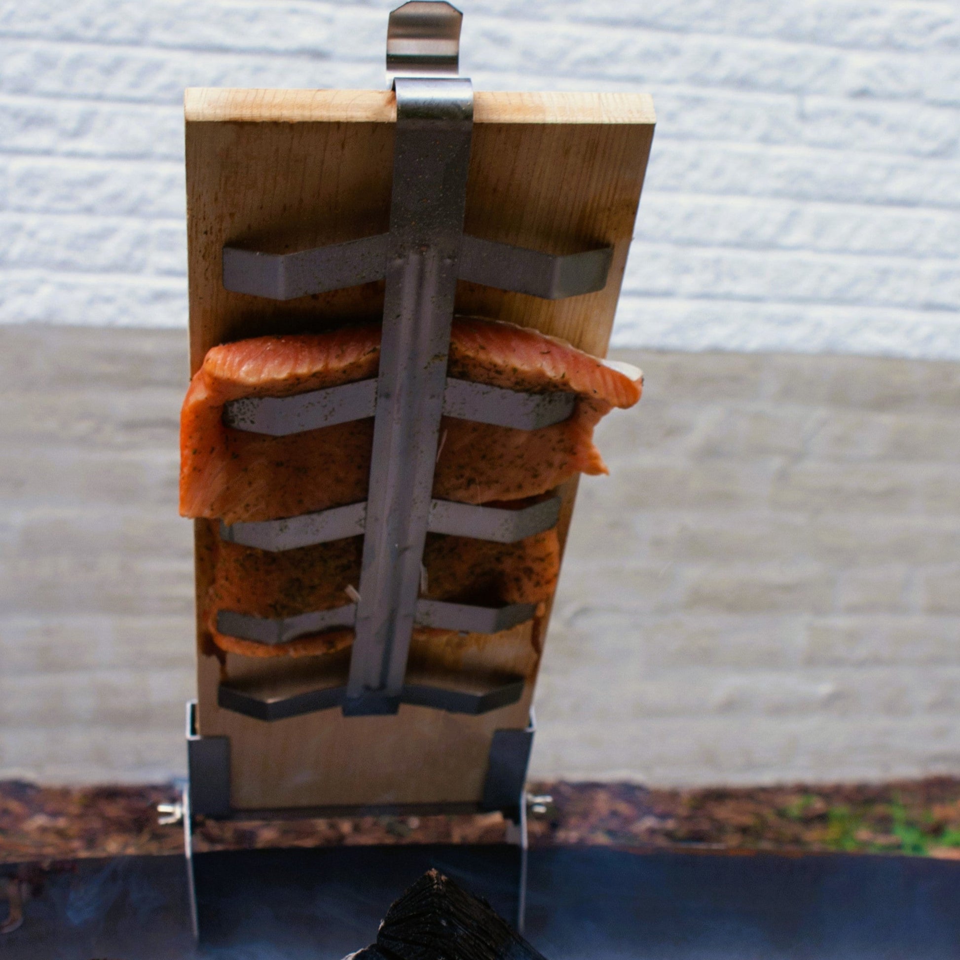 Wooden smoking device with salmon fillets over a fire