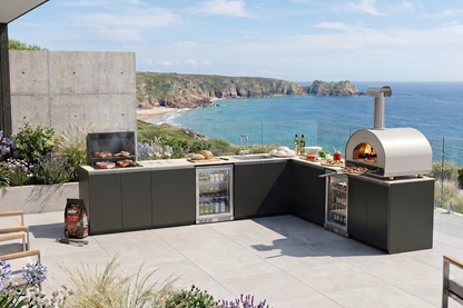 Premium outdoor entertaining kitchen with live-fire charcoal grill, pizza oven and refrigeration in a contemporary coastal garden