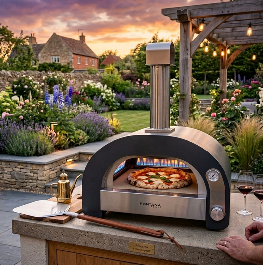 Fontana Maestro Outdoor pizza oven with a pizza cooking in a garden setting during sunset.