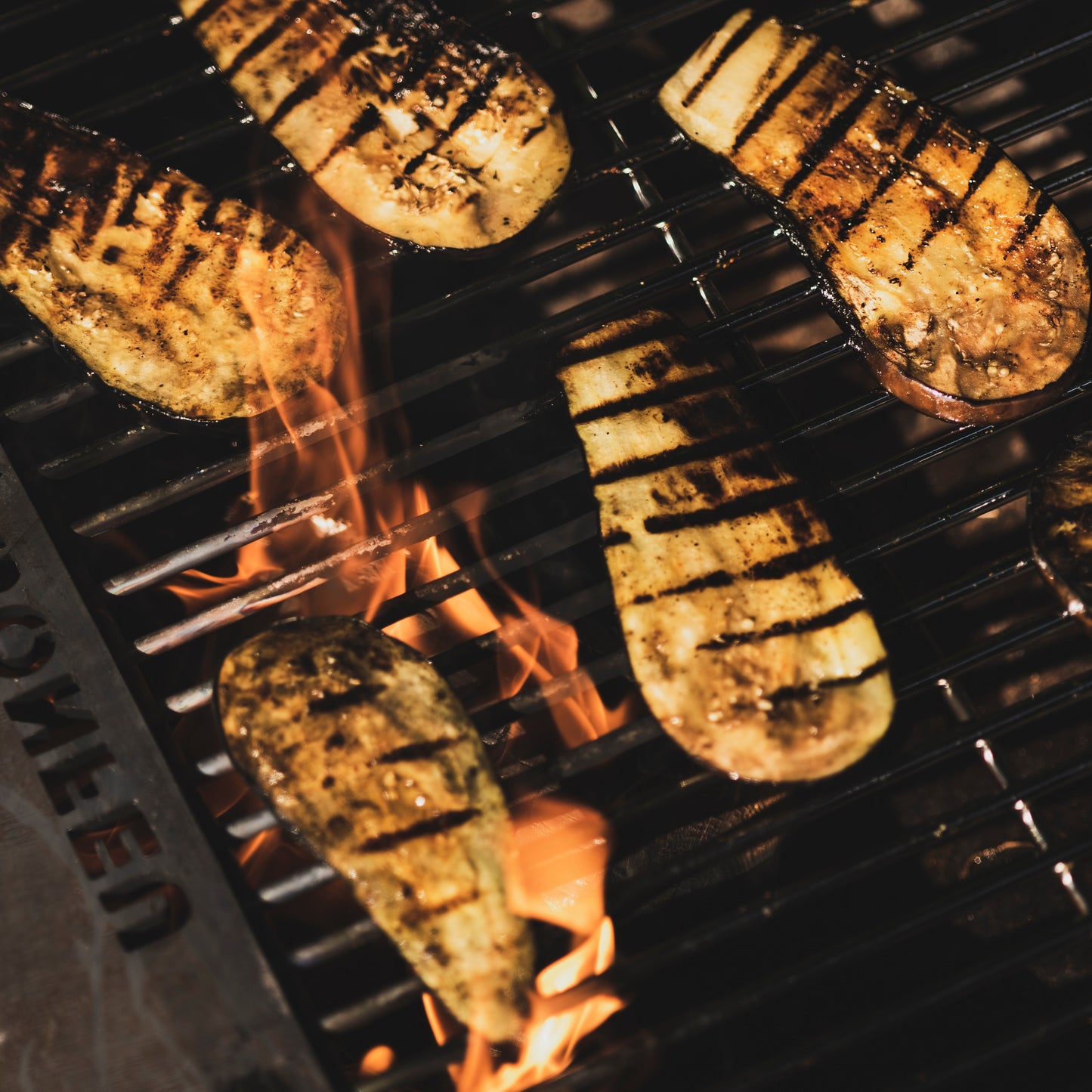 Grilled vegetables on a barbecue grill with flames below