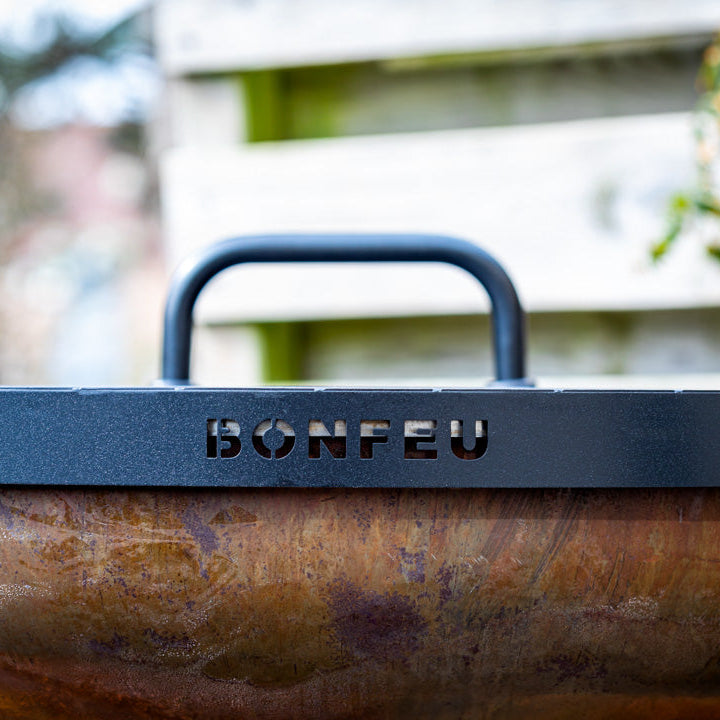 Close-up of a grill with 'BONFEU' branding outdoors.