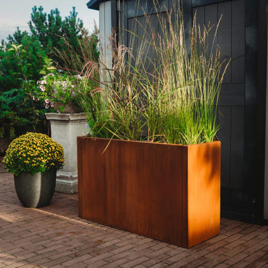 Grillsymbol corten metal planter with green plants on a brick patio