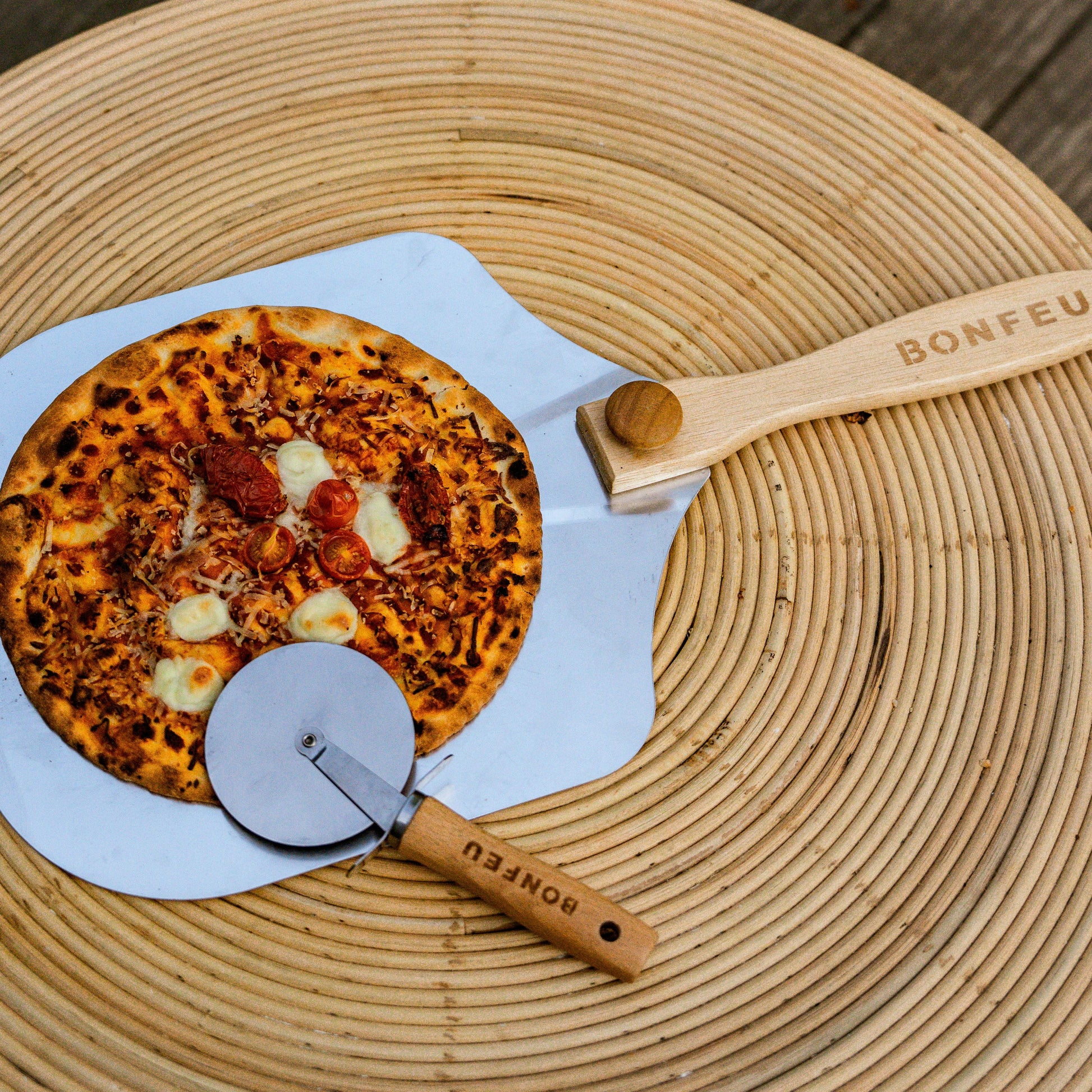 Pizza with a pizza peel and cutter on a woven mat