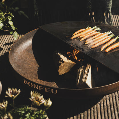 Wooden fire pit with charcoal and carrots on a textured surface