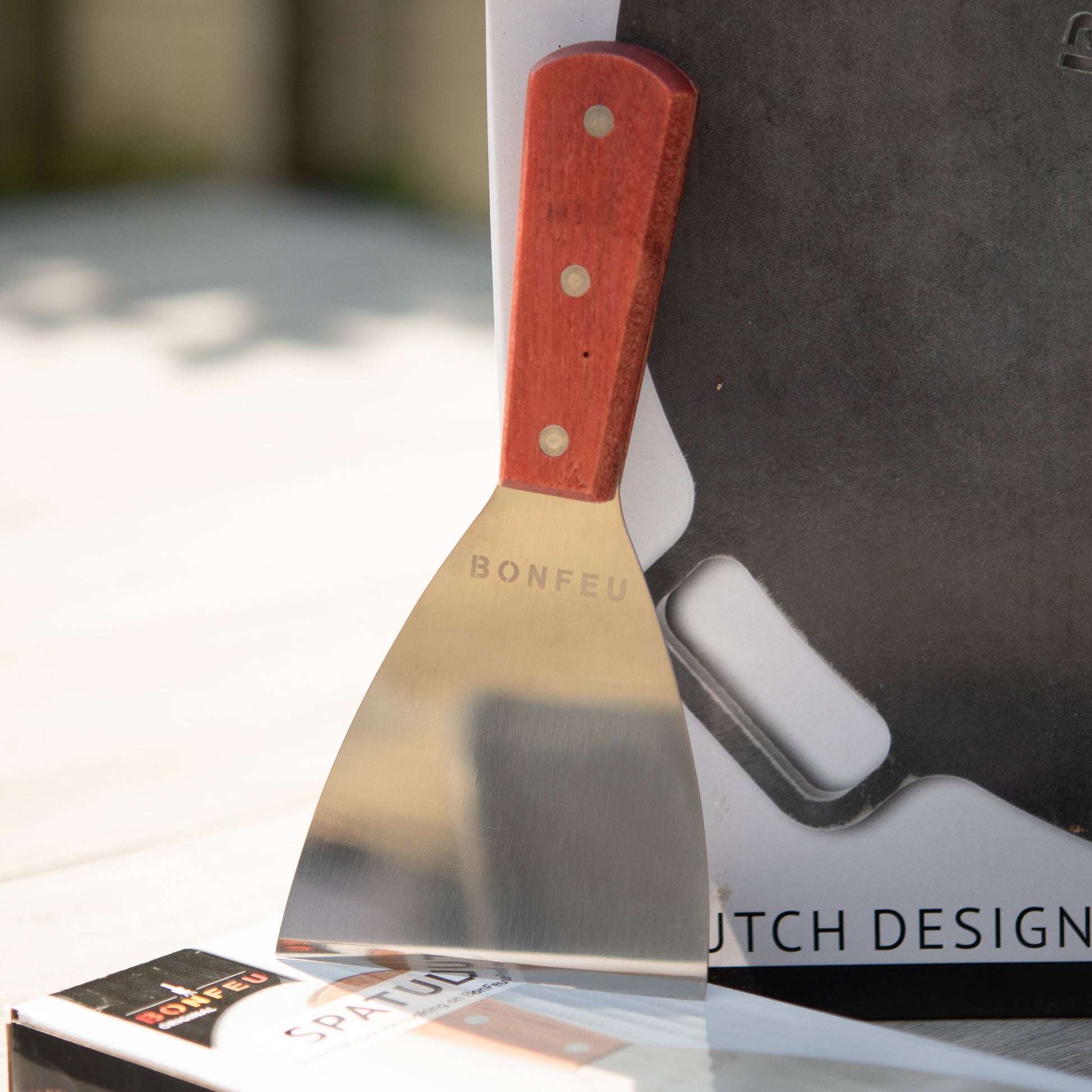 Metal spatula with red handle on a Dutch Design box