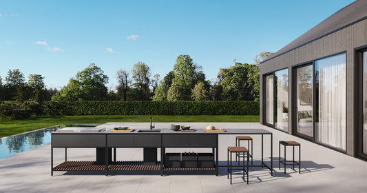 Outdoor kitchen area with a pool and modern house in the background