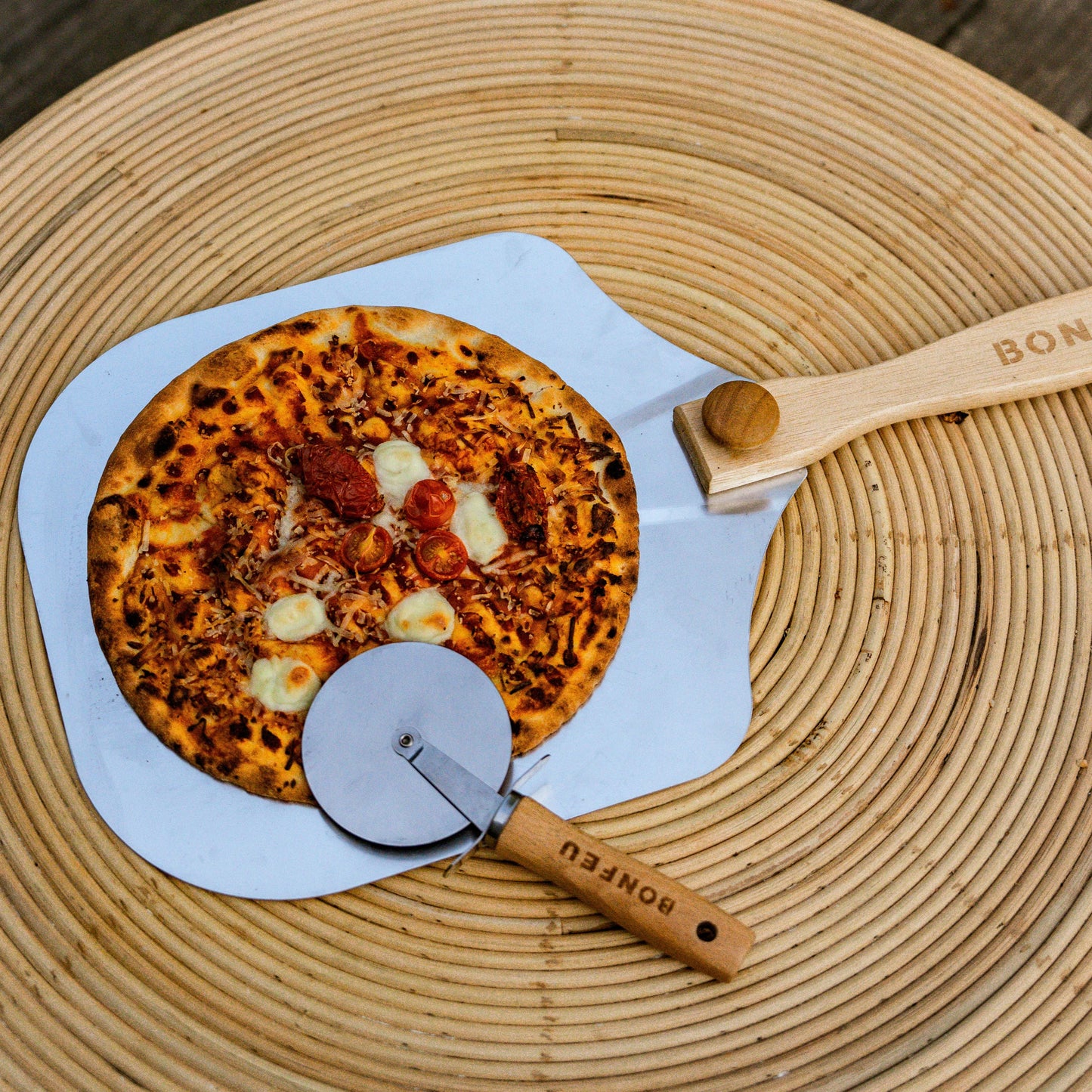Pizza with a pizza peel and cutter on a woven mat